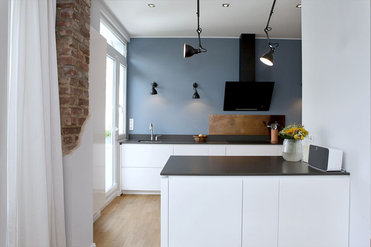 Küche offen zum Wohnraum mit farbig-gestrichener Wand und Wand- und Deckenleuchten und Parkettboden in Neuss